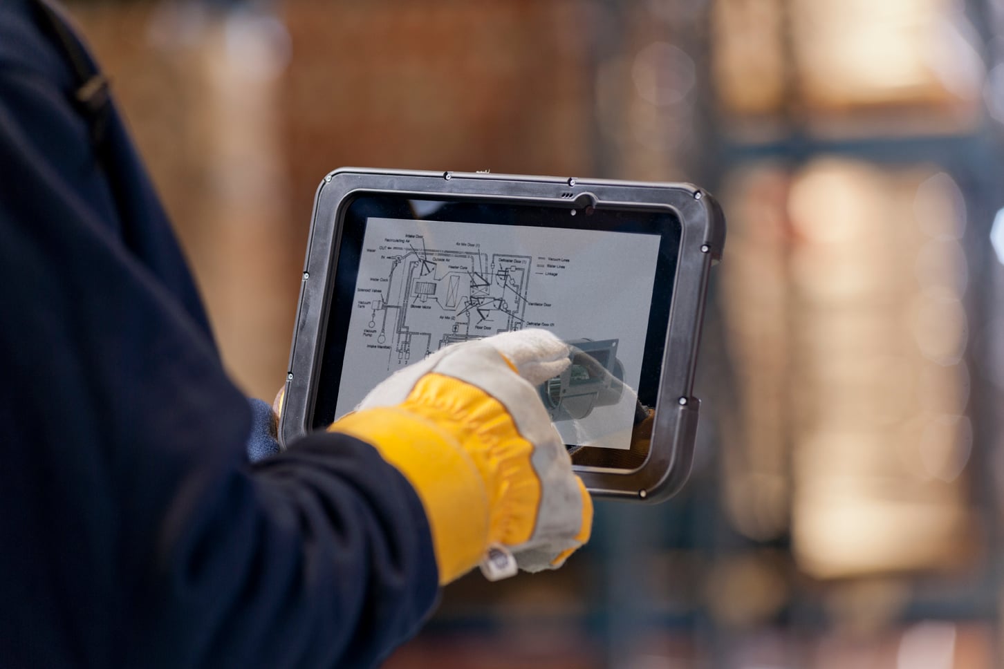 K+G machinist with gloved hand operating K+G Ai ERP on a ruggedized shop-floor tablet — viewing a part drawing and routing in production